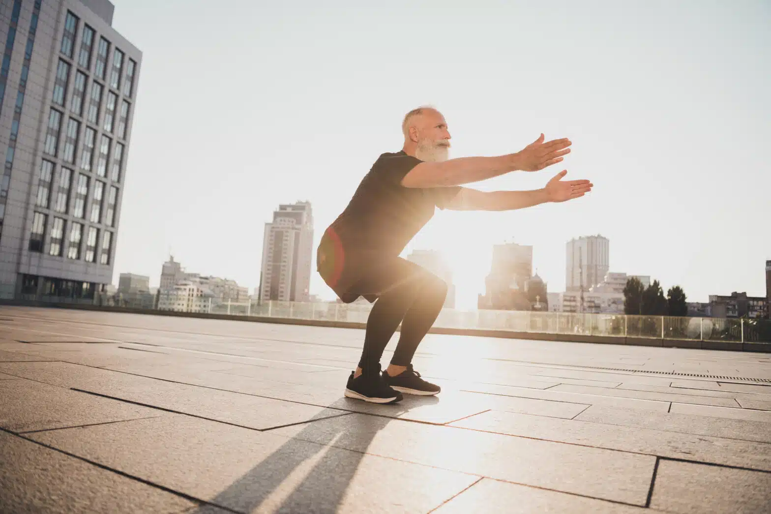 older fit man doing squats outside